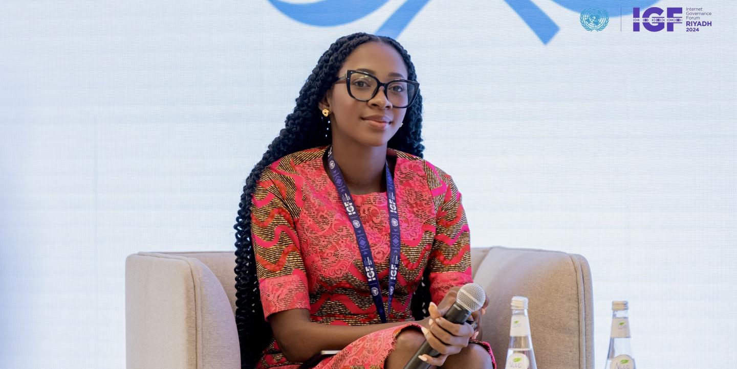 Jennifer sitting on a couch and holding microphone.