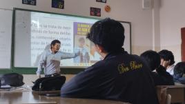 Gabriel standing in front of a white board as he talks to students.