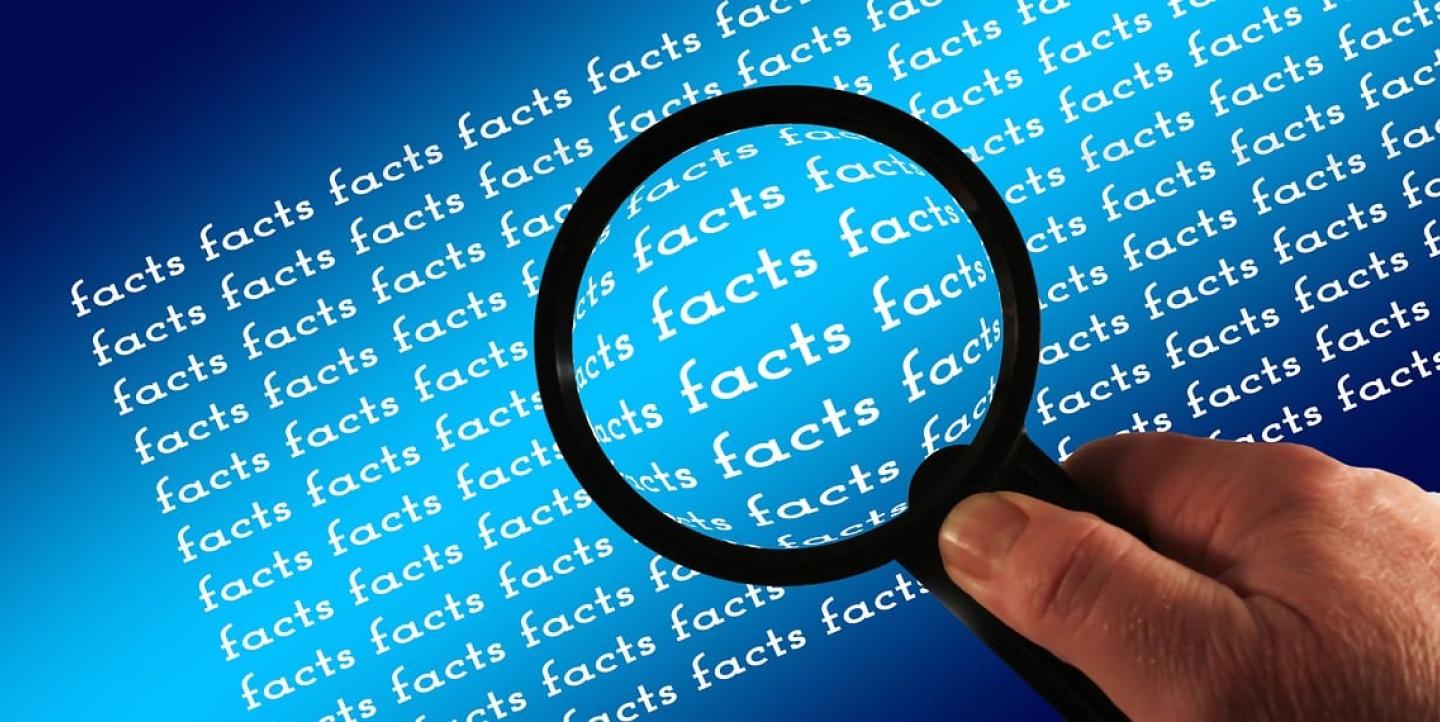 The word facts typed over and over again and a magnifying glass on top.