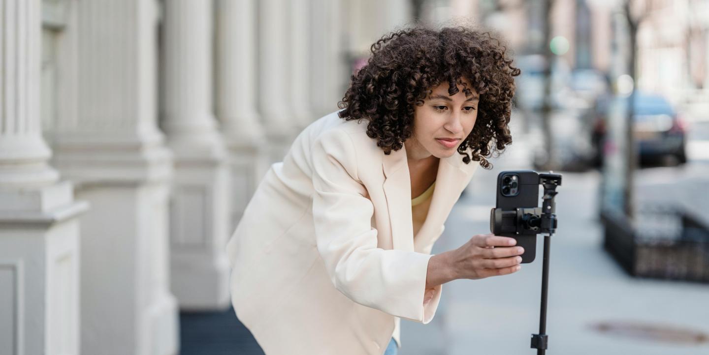 A woman setting up her phone on a tripod to record a video.