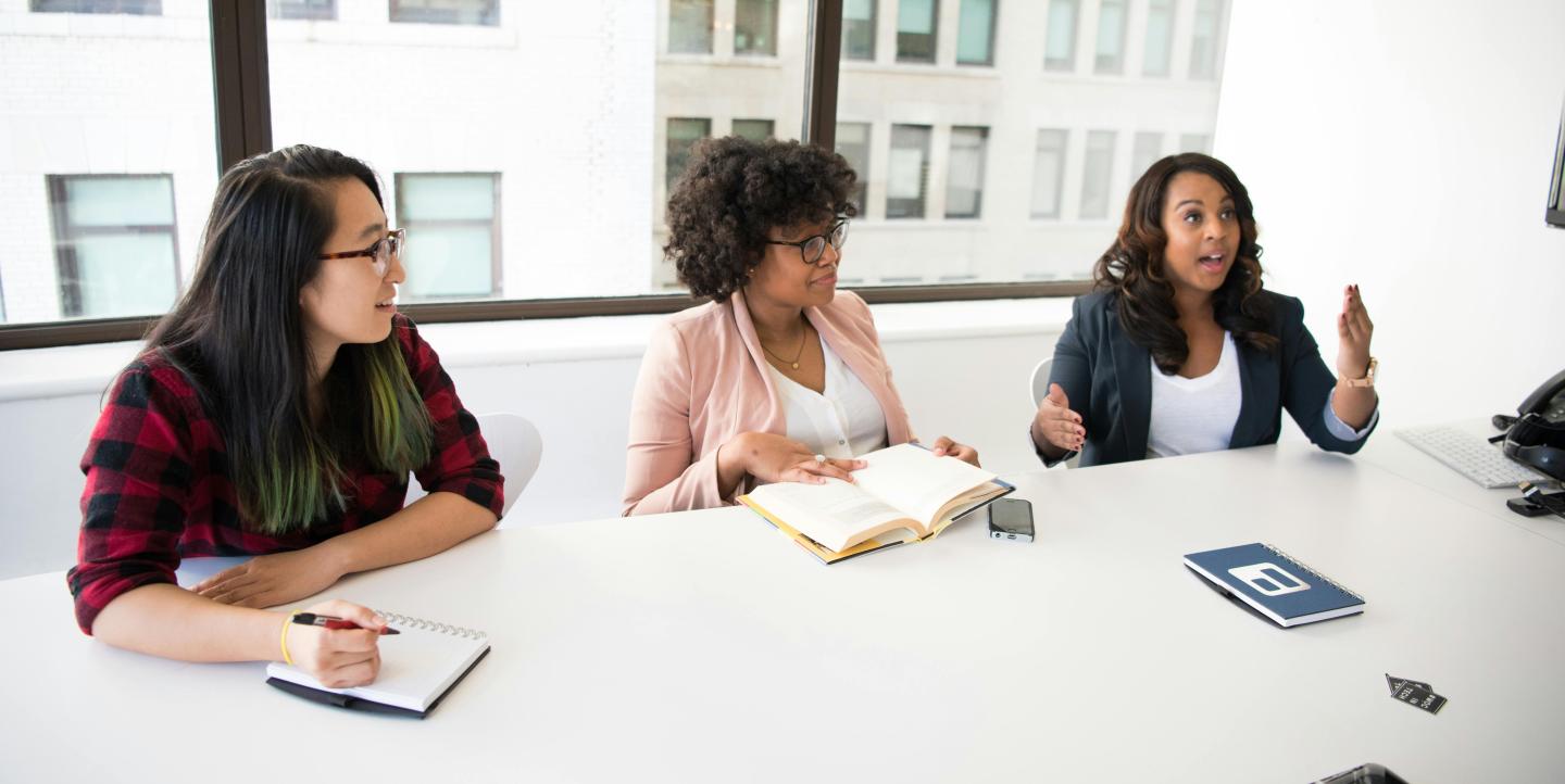 Three women at a table  in a well-lit office